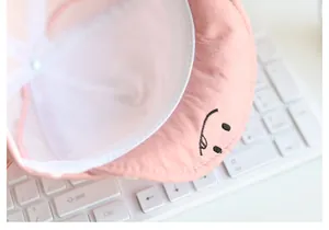 Detailaufnahme eines rosa Baby-Sonnenhuts mit gesticktem Smiley auf weicher Krempe