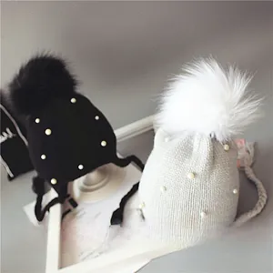 Détail de bonnets tricotés pour bébés avec pompons, perles et protège-oreilles doux