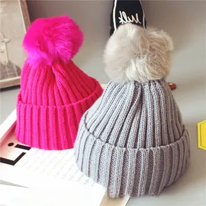 Détail de bonnets en tricot côtelé pour bébé rose et gris avec de grands pompons en peluche
