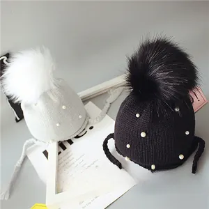 Détail de bonnets tricotés pour bébé avec pompons doux et perles blanches décoratives