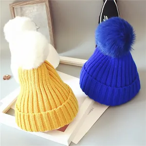 Détail du tricot des bonnets d'hiver pour bébé avec de grands pompons en fourrure