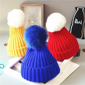 Détail de bonnets tricotés colorés pour bébés avec de grands pompons en peluche
