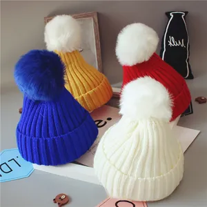 Détail de quatre bonnets tricotés pour bébé aux couleurs vives avec de gros pompons doux