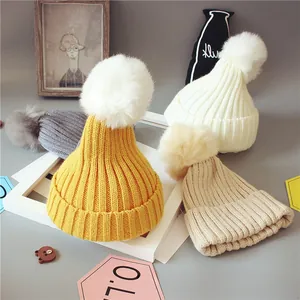 Détails de quatre bonnets en tricot colorés avec des pompons en fausse fourrure douce