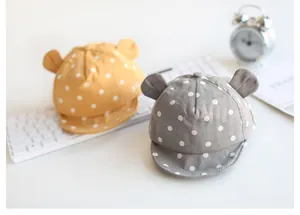 Detail von gelben und grauen Baby-Mützen mit weißen Punkten und süßen runden Ohren