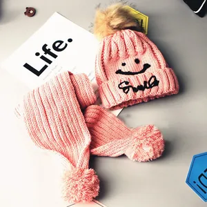 Pink knit hat and scarf set with pompom and smile embroidery for winter warmth