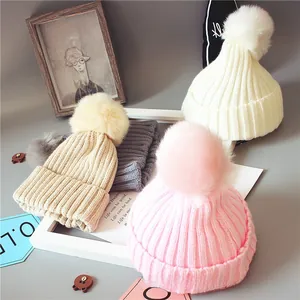 Détail du tricot de bonnets d'hiver colorés avec pompons en fausse fourrure pour bébés
