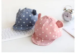 Detail von rosa und blauen Babykappen mit Punkten, weichem Schirm und süßen Ohren