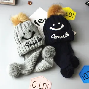 Fleece lined knit beanie and scarf set with smile embroidery and faux fur pom-poms