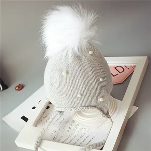 Détail du bonnet en tricot pour bébé avec pompon en fourrure et perles blanches