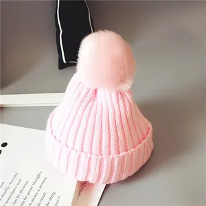 Gros plan du bonnet en tricot rose pour bébé avec un grand pompon en fourrure synthétique