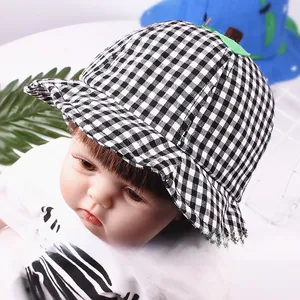 Detail of baby checkered sun hat with green leaf decoration on a model