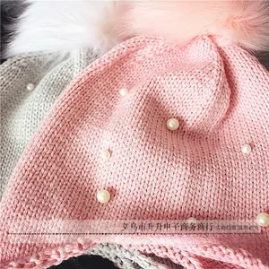 Gros plan du bonnet en tricot rose orné de perles élégantes et d'un pompon en fausse fourrure