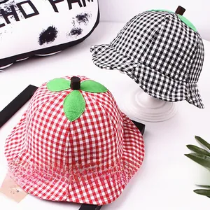 Detail of red and black checkered baby sun hats with green leaf fruit decorations