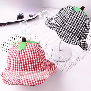 Detail of red and black gingham bucket hats with green leaf tops for children