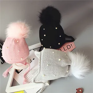 Bonnet tricoté pour bébé avec perles, cache-oreilles et grands pompons en trois couleurs