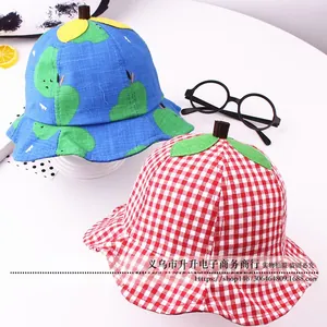Detail of kids bucket hats in blue fruit and red plaid patterns with leaf accents
