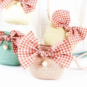 Detailed macro view of woven straw crossbody bags with large gingham bows and pearl charms