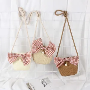 Detailed view of straw woven kids crossbody bags with plaid bows and pearl accents