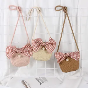 Detailed view of woven straw bags for kids with plaid bows and pearl charms in three colors