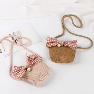 Detail of handmade mini straw crossbody bags with plaid bows and pearl accents