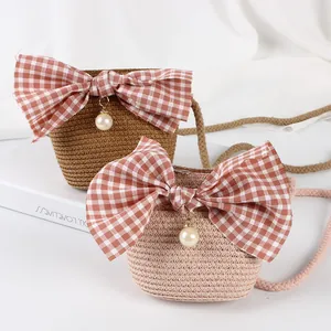 Detail of mini straw bags with red gingham bows and pearls on white textured fabric