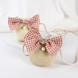 Detailed straw shoulder bag featuring a plaid bow and pearl pendant for kids