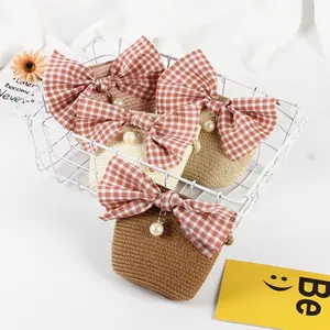 Close-up of handmade straw bags with checkered bows and pearl pendants in a basket