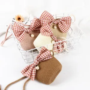 Detail of straw woven crossbody bags with large plaid bows and pearl charms for girls