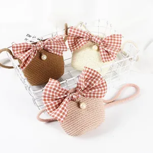 Close-up of woven straw bags with checkered bows and pearl charms in various colors