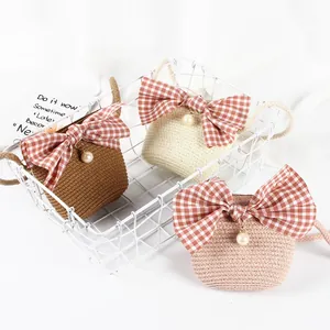 Detailed view of handmade straw crossbody bags featuring red gingham bows and pearl charms