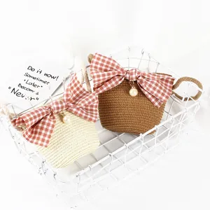 Detail of mini straw bags with red gingham bows and pearl charms in a white basket