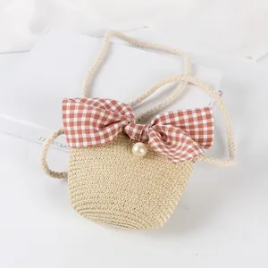 Detailed texture of beige woven straw bag with large plaid bow and pearl accent