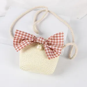 Detail of child's straw crossbody bag with orange plaid bow and pearl bead accent