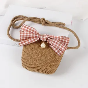 Detailed view of handmade straw woven bag with gingham bow and pearl pendant