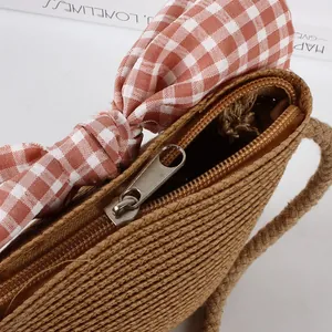 Detail of children's straw bag with silver zipper closure and red plaid bow decoration