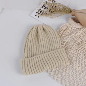 Close-up of thick ribbed knit texture on a beige winter beanie with folded cuff