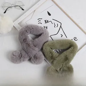 Gros plan sur des écharpes croisées en fausse fourrure grise et verte avec pompons