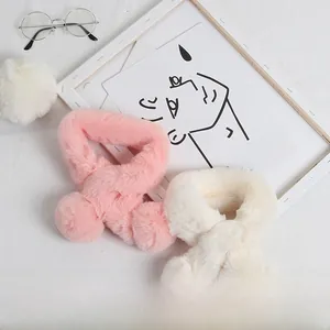 Détail d'une écharpe croisée en peluche pour enfants avec pompons doux en rose et blanc