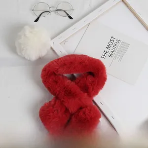 Détail d'une écharpe en peluche rouge pour enfants avec pompons en fausse fourrure