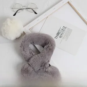 Vue détaillée d'une écharpe en peluche grise avec pompons et texture fausse fourrure