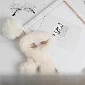 Détail de l'écharpe croisée en fausse fourrure crème avec pompons pour enfants