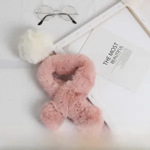 Détail d'une écharpe en fausse fourrure rose pour enfants avec pompons moelleux