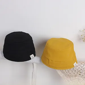 Detail von Kinder Fischerhüten in Schwarz und Gelb mit minimalistischen Smiley-Stoffetiketten