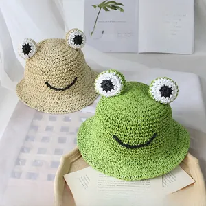 Détail de chapeaux de paille mignons au design de grenouille en beige et vert pour l'été