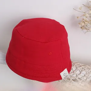 Detail eines roten Fischerhuts aus Segeltuch mit weißem Smile-Label und Baumwolltextur