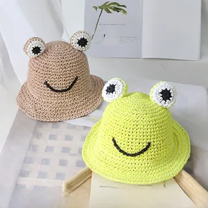 Détail d'un chapeau en paille fait main avec yeux de grenouille et visage souriant