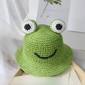 Détail d'un chapeau de soleil grenouille verte en paille tissée avec de grands yeux