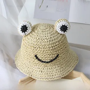 Vue détaillée du chapeau de paille beige en forme de grenouille avec yeux décoratifs