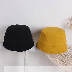 Dettaglio di cappelli alla pescatora per bambini in tela di cotone nero e giallo cuciti